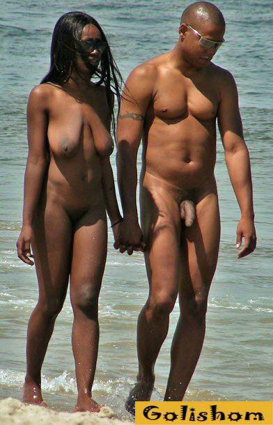 Naked nudists walk in pairs on the beach