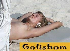 Toni Garrn sunbathes topless on the beach
