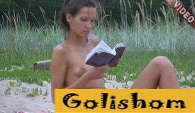 Beautiful naturist on the beach reading a book-video